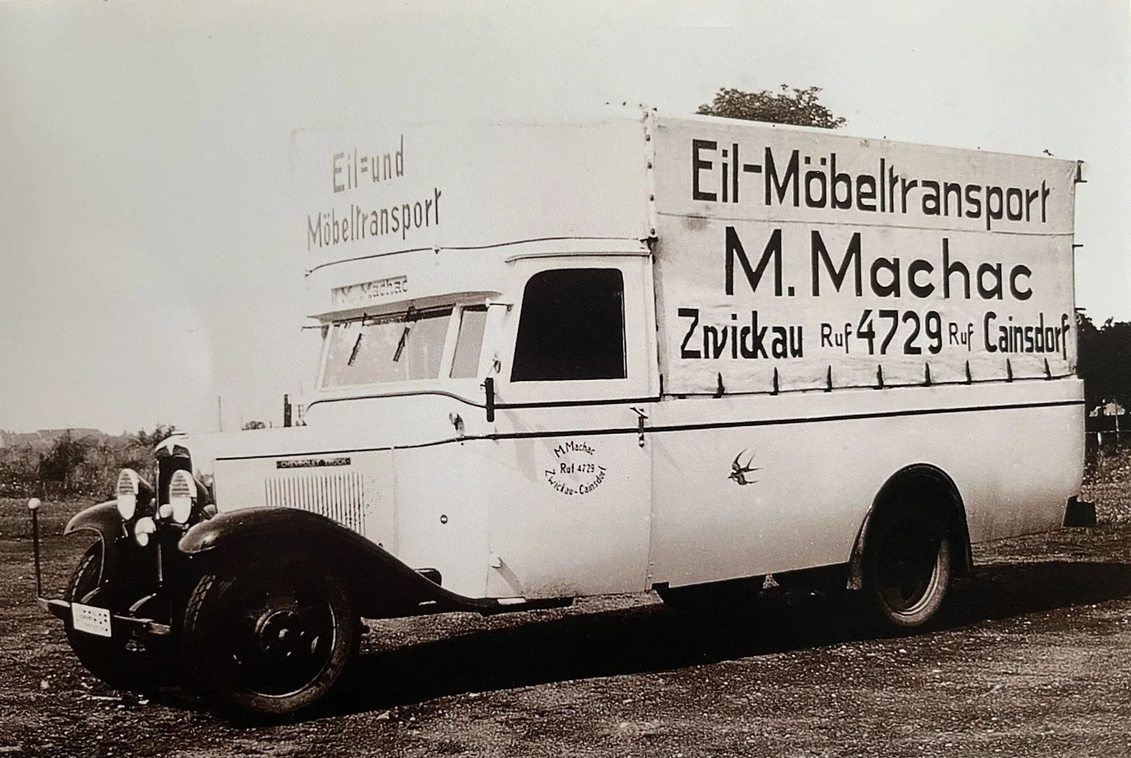 A Machac express furniture lorry lettered “Eil-Möbeltransport M. Machac, Zwickau Ruf 4729 Cainsdorf”, with a swallow painted on the cab door.